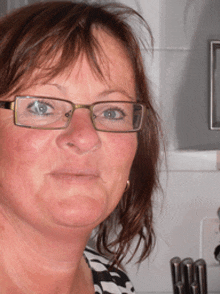 a close up of a woman wearing glasses and a black and white shirt