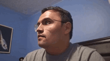 a man wearing glasses is making a funny face in a room .