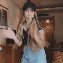 a woman wearing a black hat and blue shorts is dancing