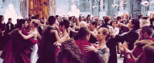 a large group of people are dancing at a ball in a ballroom .