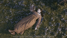 a woman in a brown dress is laying in a field of flowers with the words property of red planet pictures above her