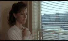 a woman looking out of a window with blinds on it