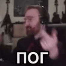 a man with a beard is wearing headphones and making a gesture with his hands .