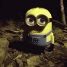a toy minion is sitting on the ground in the dark .