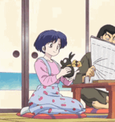 a woman is kneeling down holding a stuffed animal while a man reads a newspaper .