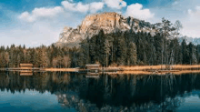 a lake surrounded by trees and mountains with a mountain in the background