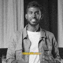 a black and white photo of a man wearing a white shirt and a jacket that says save
