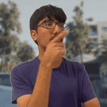 a man wearing glasses and a purple shirt is pointing