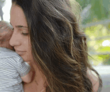 a woman is holding a baby in her arms and looking down .