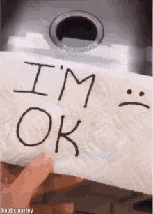 a person holding a paper towel that says i 'm ok