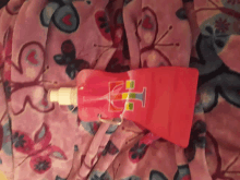 a pink bottle with the letter h on it is on a pink blanket