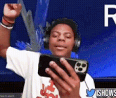 a young man wearing headphones is holding a cell phone in his hand ..