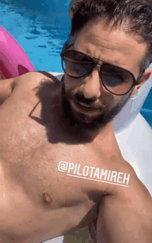 a shirtless man with a beard wearing sunglasses is floating in a pool .