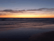 a sunset over a body of water with waves coming in