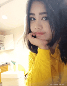 a woman in a yellow sweater is taking a selfie on april 11th