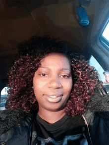 a woman with curly hair is smiling for the camera in a car