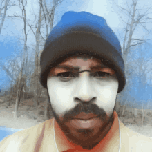 a man with a beard and white paint on his face is wearing a blue hat