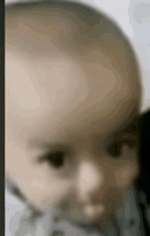 a blurry picture of a baby 's face with a gray shirt