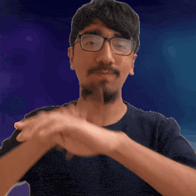 a man wearing glasses and a beard is making a gesture with his hands