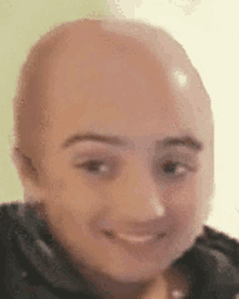 a close up of a person 's face with a bald head and smiling .