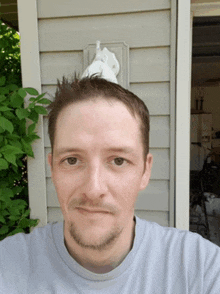 a man taking a selfie in front of a house with a towel on his head