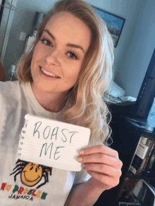 a woman is holding a sign that says roast me