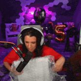 a woman wearing headphones holds a box in front of a microphone with a balloon that says happy birthday on it