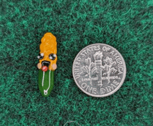 a corn on the cob with a face is next to a one dime coin .