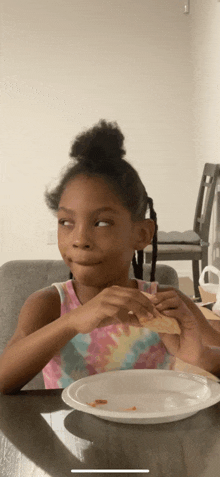 a little girl sitting at a table with a plate of food