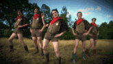 a group of men in shorts and cowboy boots stand in a field