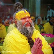 a man with a beard is wearing a yellow robe and has a yellow flower on his forehead