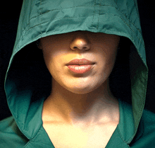 a woman wearing a green hooded jacket covers her face