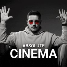 a man wearing red sunglasses is sitting in a chair with his hands in the air under the words absolute cinema