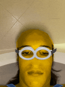 a man in a bathtub has a yellow face and white goggles on