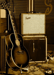 a guitar sits in front of a supro amp