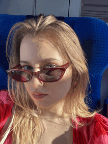 a woman wearing sunglasses is sitting in a blue seat