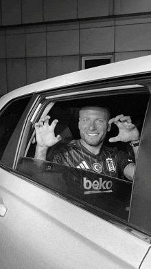 a man in a beko shirt is sitting in a white car