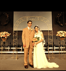 a bride and groom pose in front of a wrought iron archway