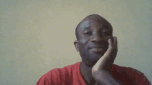 a man in a red shirt is smiling with his hand on his chin