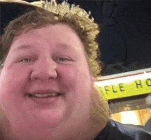 a fat man with a beard is smiling for the camera while standing in front of a waffle house .