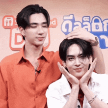two young men are standing next to each other with one holding the other 's head .