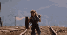 a girl in overalls is standing on train tracks holding a radio