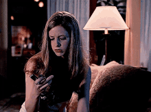 a woman is sitting on a couch holding a cell phone