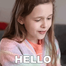 a little girl is saying hello with a smile on her face