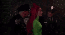 a woman in a green costume is fighting a man in a brick room .