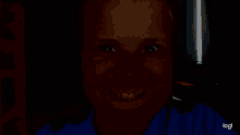 a close up of a person 's face in the dark with a blue shirt on .