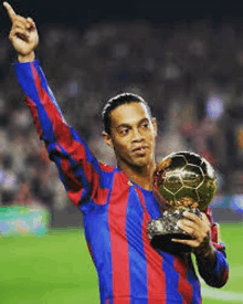 a soccer player is holding a trophy on a field .