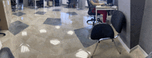 a woman sits at a desk in an office with a laptop