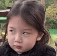 a little girl is making a funny face while looking at the camera .