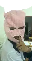 a person wearing a pink ski mask is holding their finger to their lips .